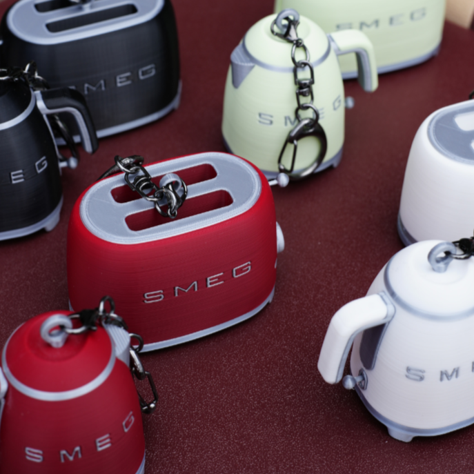 Collection of SMEG-themed keychains on a red surface
